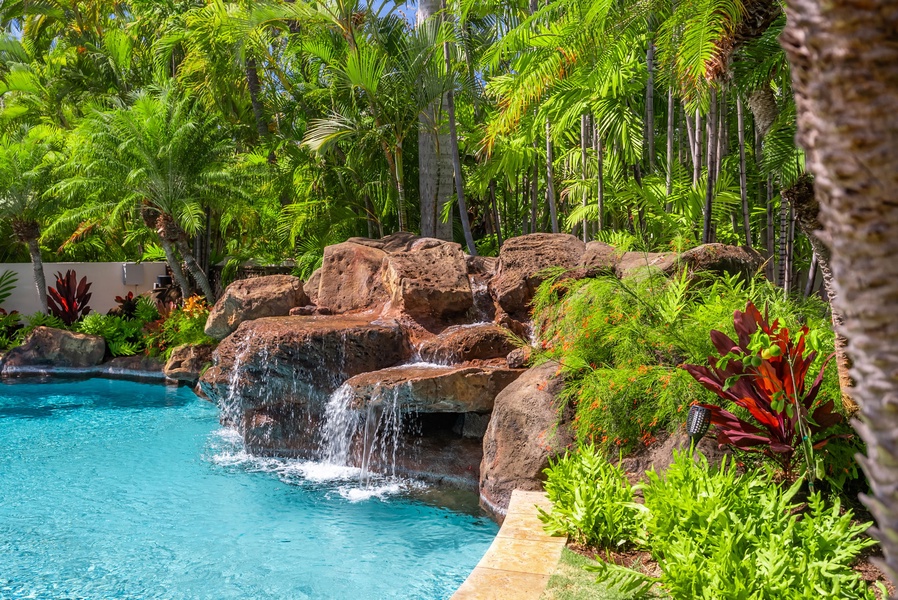 Tropical pool with a natural rock waterfall feature, providing a private oasis for relaxation.