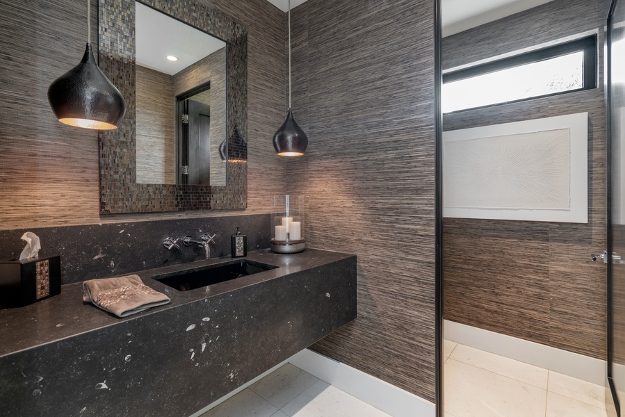 The guest bathroom features a modern contrast design and a walk-in shower, creating a luxurious spa-like retreat after a day exploring Hawaii’s beaches.