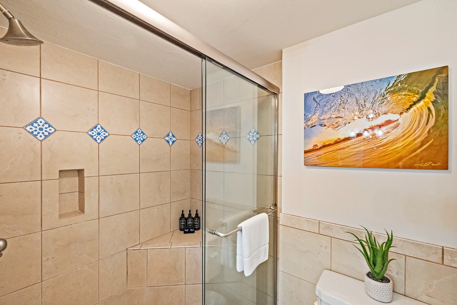 The bathroom showcases a walk-in shower with elegant tile detailing and a glass door, offering a serene space to unwind