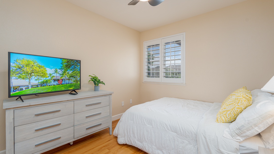 The third guest bedroom with a dresser, television and cheerful window.