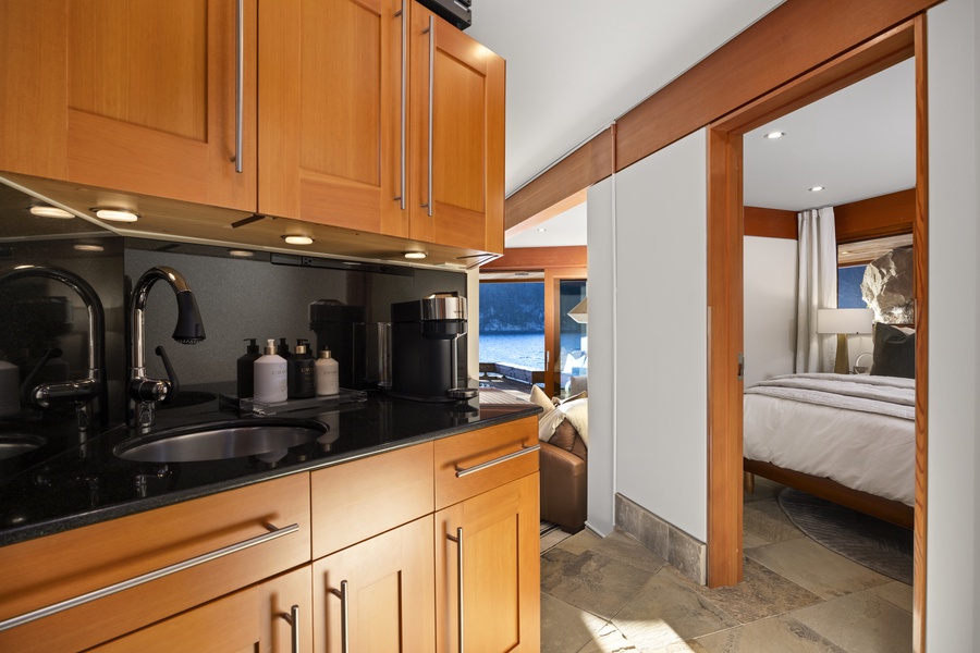 Your sleek galley kitchen features warm wood cabinetry and modern appliances, flowing seamlessly into your cozy bedroom sanctuary.