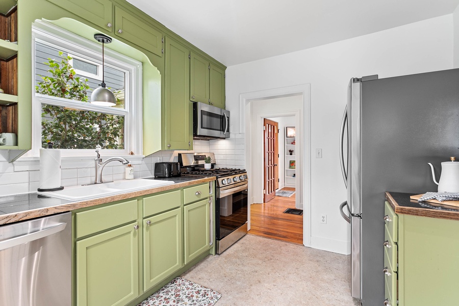 This bright kitchen features butcher block counters, stainless steel appliances, and fresh green cabinetry with mountain-town charm.