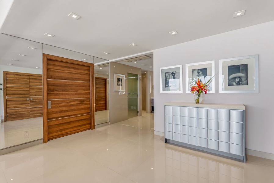 Step into a sophisticated entryway with gleaming floors, elegant artwork, and fresh florals welcoming you. Modern design meets comfort in your private retreat.