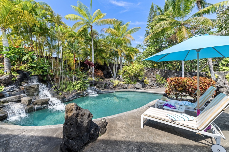 Your private tropical oasis awaits with a stunning lagoon-style pool, cascading waterfall, and comfortable loungers under swaying palms.