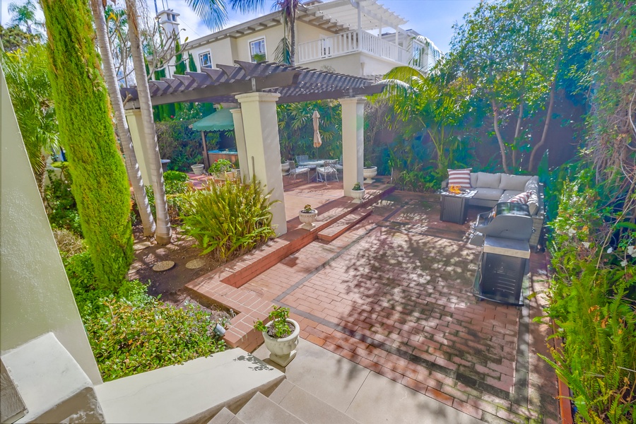 The pergola-covered seating area is ideal for lounging, dining, or simply soaking up the peaceful ambiance of the surrounding garden.