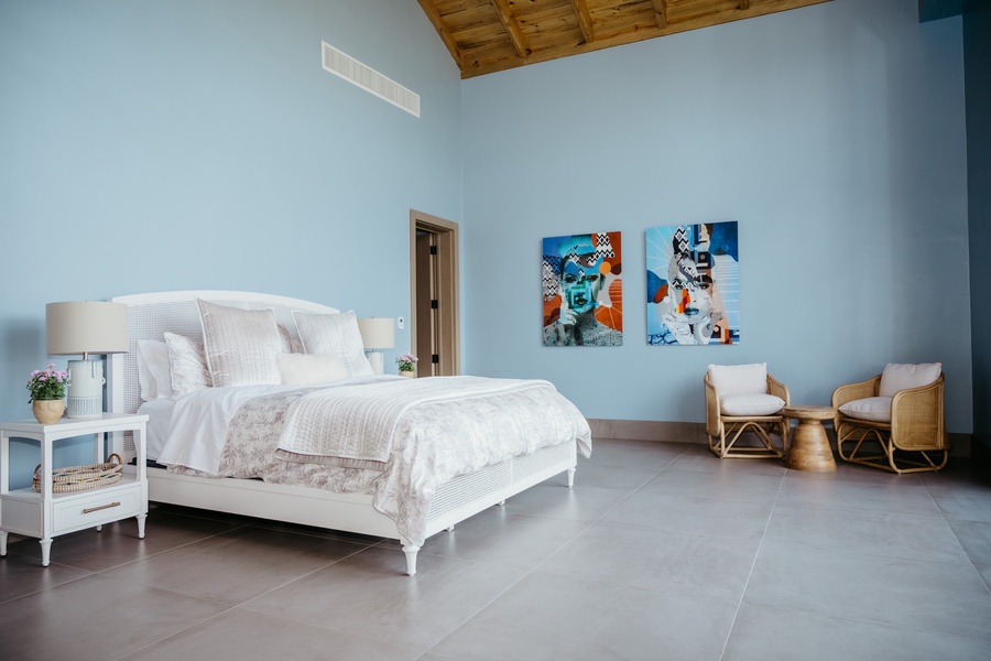 The guest bedroom features a comfortable bed, a seating area and two contemporary artwork.