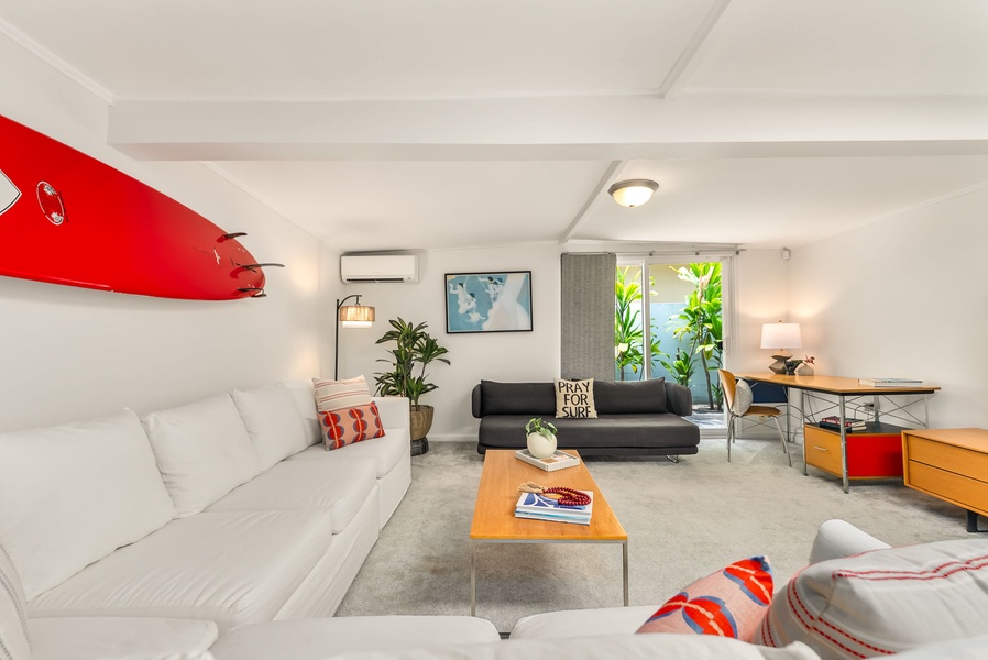 Settle into your stylish living space with bright coastal vibes, surfboard art, and comfy seating—perfect for relaxing after beach adventures or planning your next outing.