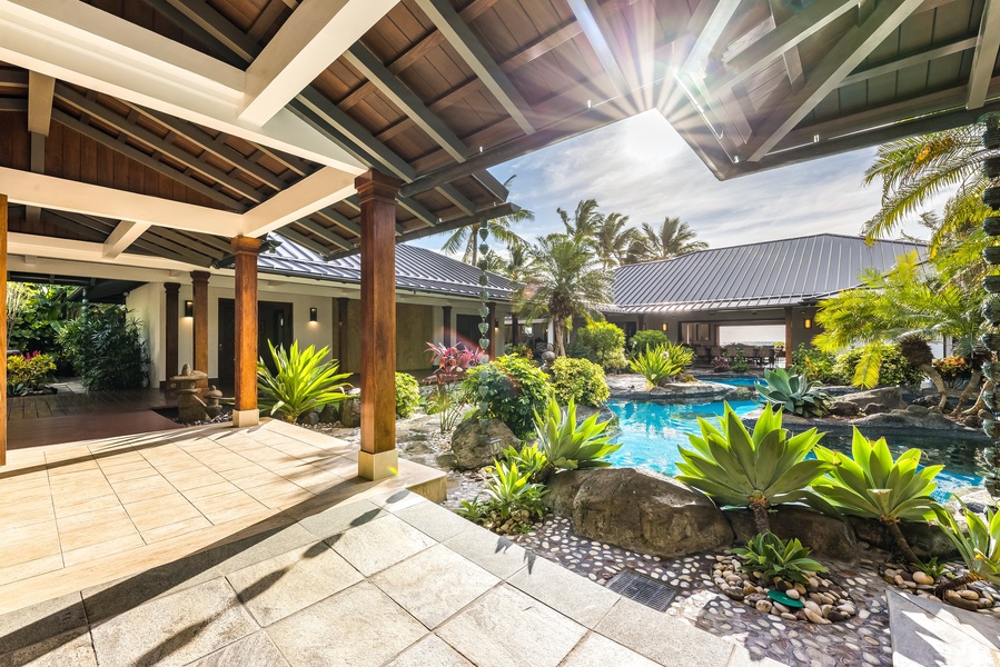 Dappled sunlight filters through the covered lanai, offering shaded garden lounging.