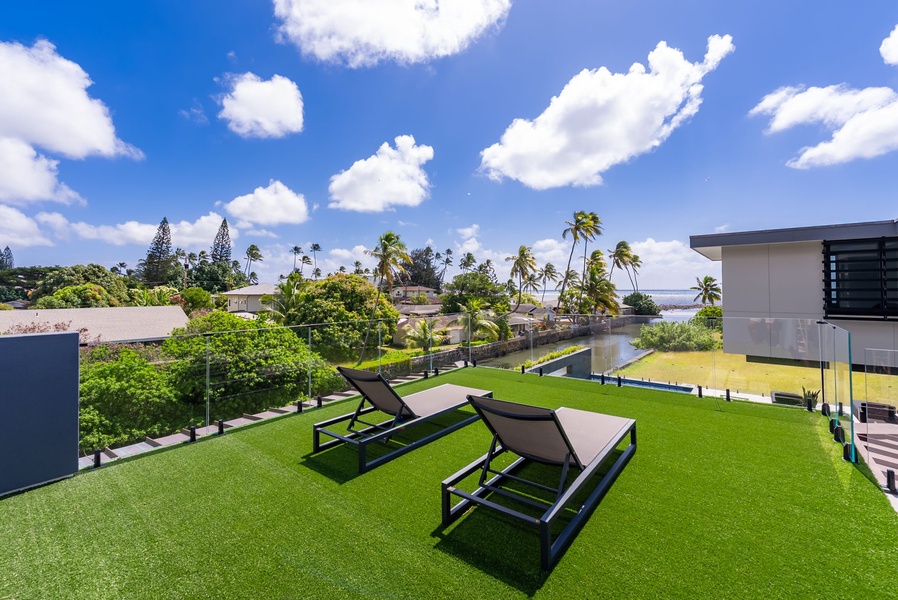 Unwind on the oceanfront lawn with loungers, open sky, and coastal views.