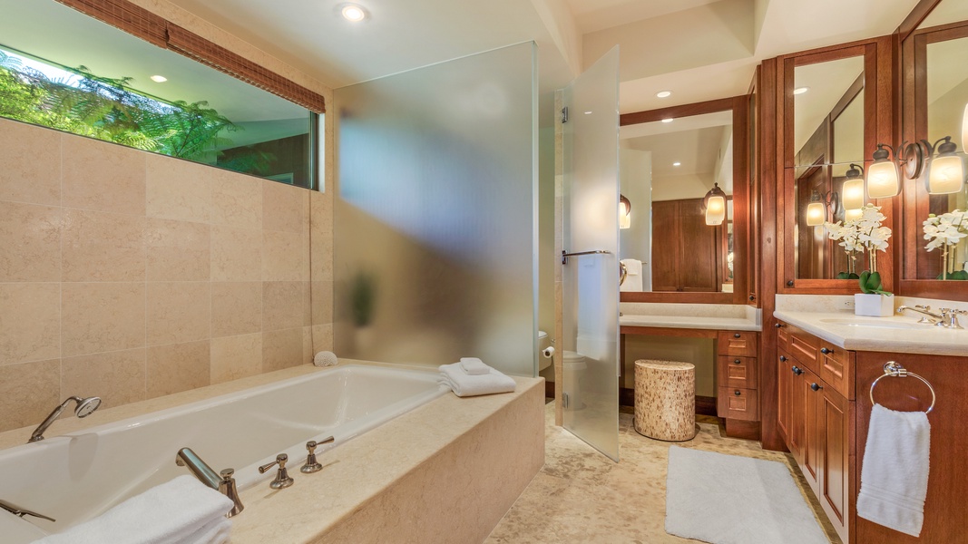 Primary bath with oversized soaking tub and frosted privacy glass around the commode.