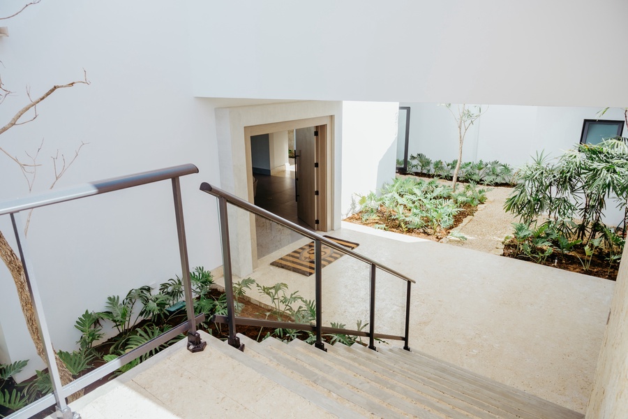A modern staircase leading to the courtyard area with lush garden beds.