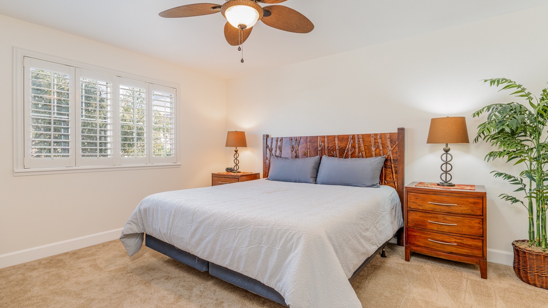 The primary guest bedroom with a ceiling fan and scenery.