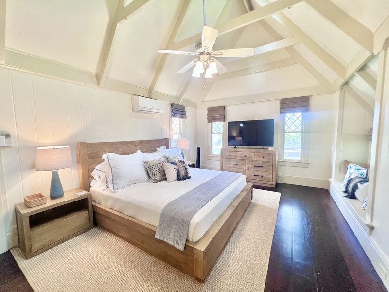 Primary bedroom with a king-size bed, elegant finishes, and natural light pouring in through large windows