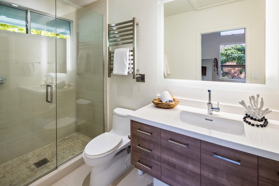 Crisp, clean bathroom with double sinks and glass-enclosed shower for your comfort.