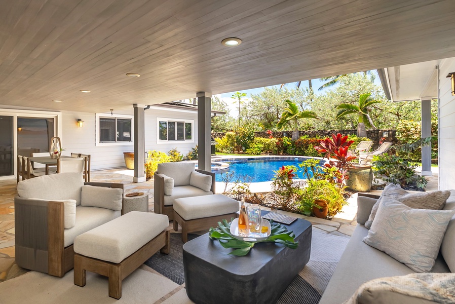 Covered lanai with plush seating and views of the private pool and garden.
