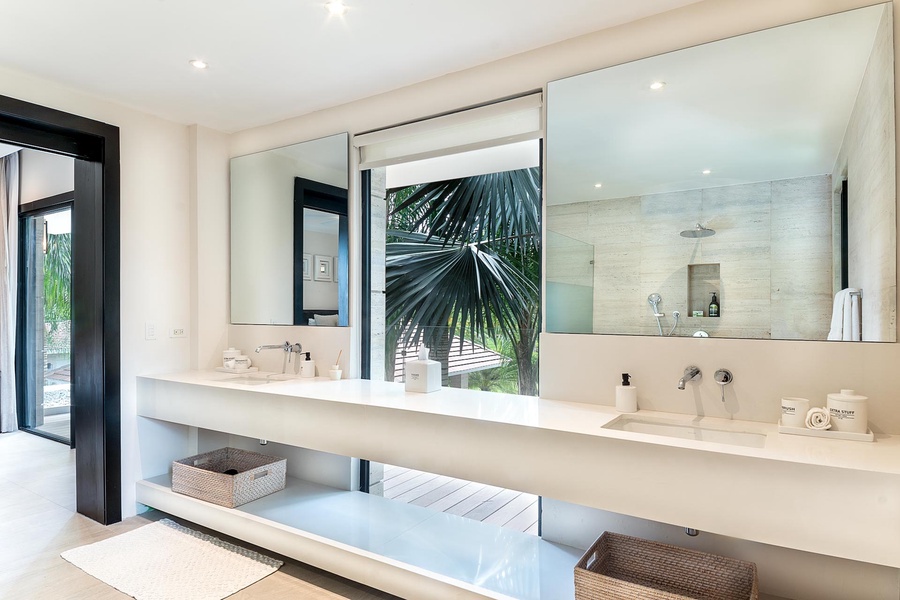 Bright and airy bathroom featuring dual sinks and a large walk-in shower.