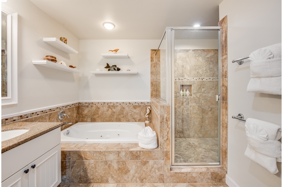 Luxurious jetted tub and glass shower bestow the primary bathroom