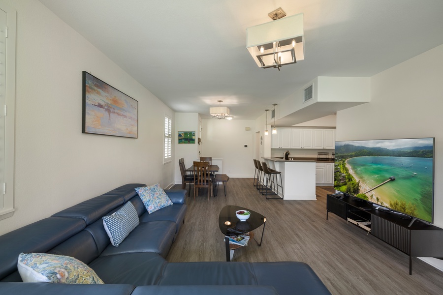 Relax in your spacious open-plan living area with comfortable seating, modern kitchen, and large TV for perfect evenings in.