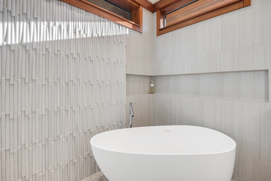 Primary ensuite bathroom sumptuous soaking tub with textured tile details creating a serene ambiance.