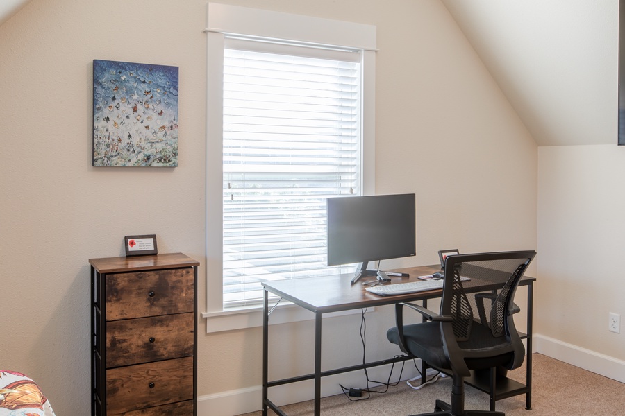 This bedroom also has a convenient dedicated workspace including monitor, keyboard, cable adapters, and mouse with pad