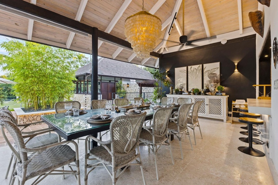 Enjoy open-air dining in this elegantly designed space, featuring a large dining table with comfortable wicker chairs.