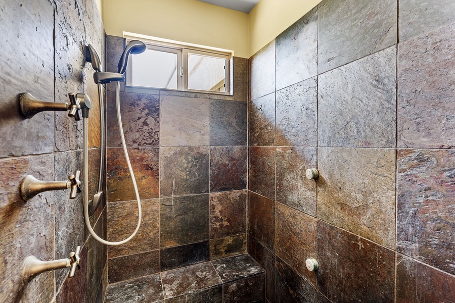 Luxurious slate-tiled walk-in shower with multiple shower heads for a spa-like experience.