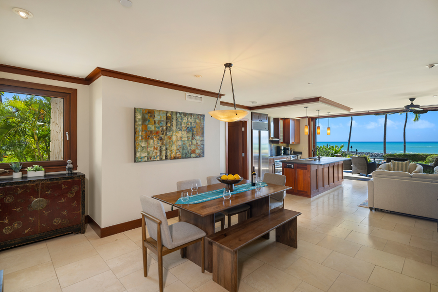 A spacious and airy living area with a dining table and lounge, opening up to ocean views.