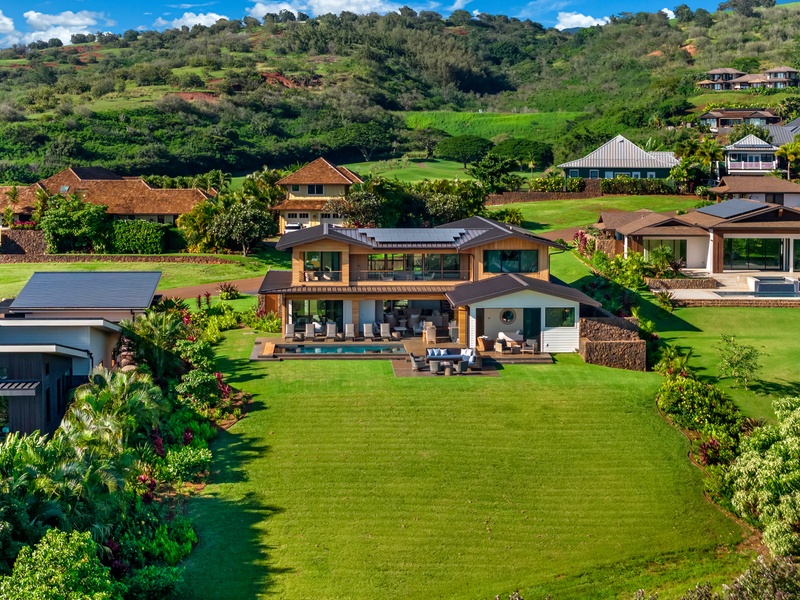 Stunning modern estate nestled in lush tropical hills with expansive lawns and swimming pool surrounded by vibrant landscaping.
