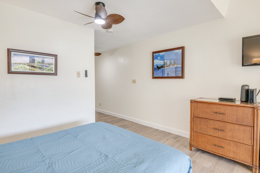 Unwind in your peaceful bedroom featuring a comfortable bed, coastal artwork, and gentle ceiling fan for perfect relaxation.