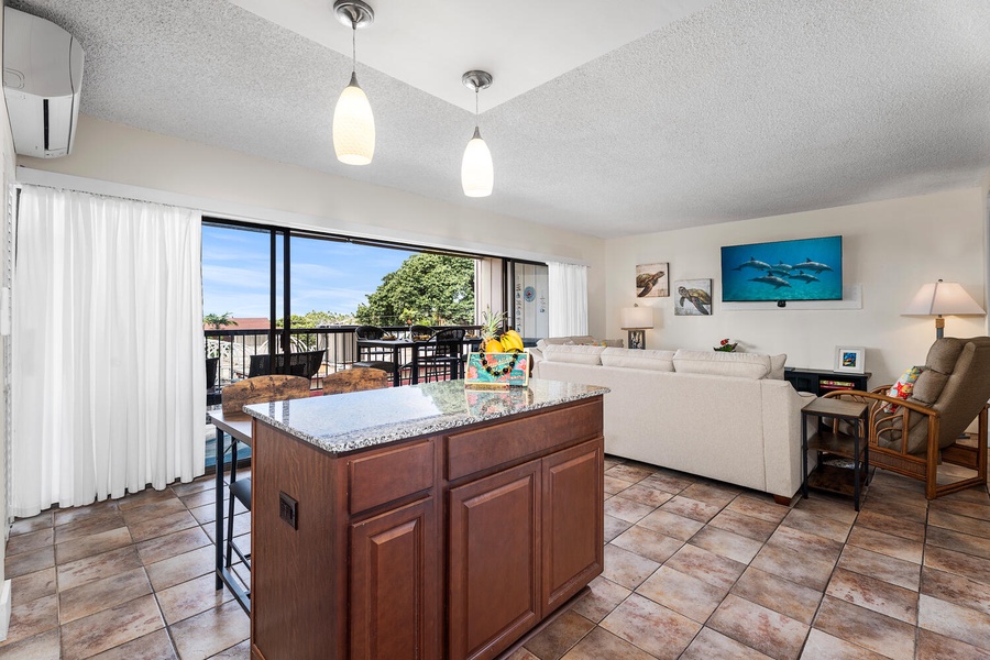 Relax in your open-concept space where kitchen island flows into living room, with lanai doors opening to tropical views.