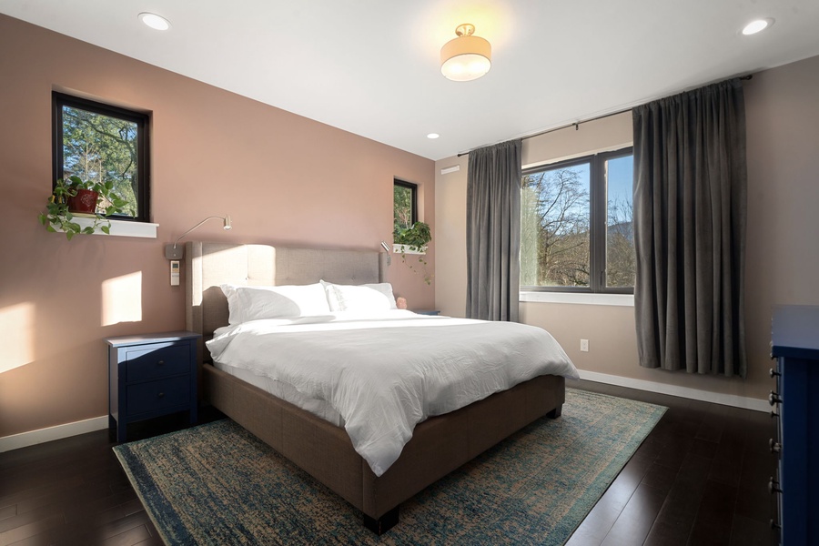 Rest peacefully in your stylish bedroom with crisp linens, warm natural light, and serene treetop views beyond your window.