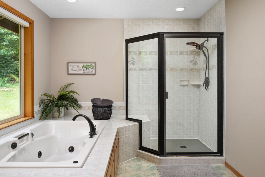 Ensuite bathroom with hot tub and shower with glass enclosure