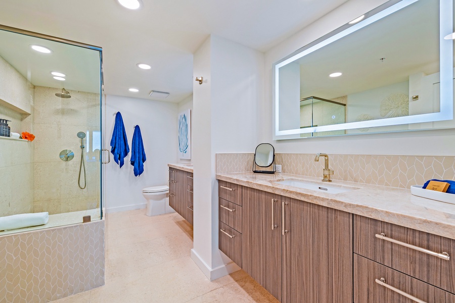 The bathroom offers a modern walk-in shower and plenty of counter space with a sleek vanity for a comfortable stay.