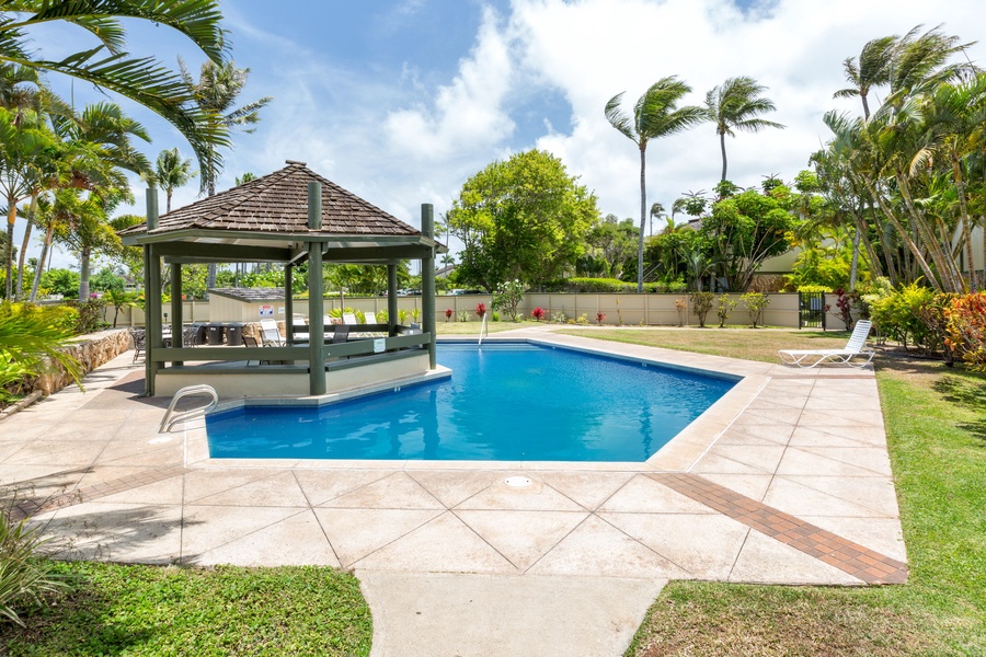 Community pool surrounded by palms and open lawn.