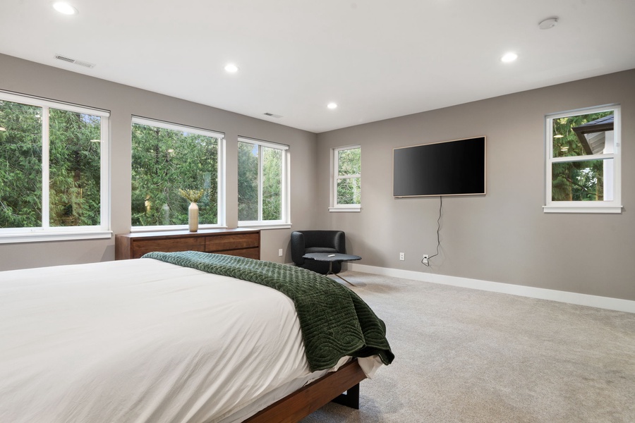 Sink into your peaceful bedroom retreat with garden views, modern TV, and cozy seating nook for ultimate relaxation.