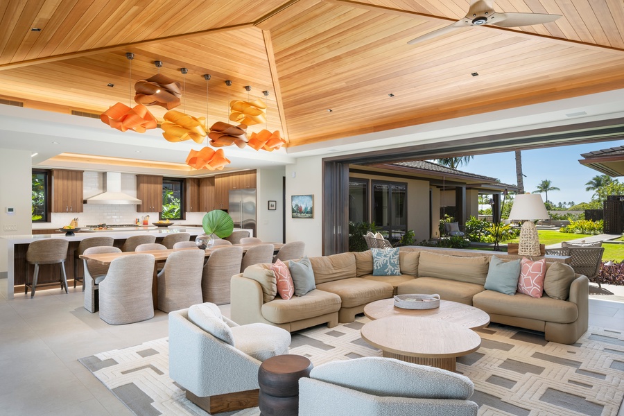 Sink into plush sectional seating beneath soaring wood ceilings while vibrant pendant lights create a warm glow in this open-concept living space.