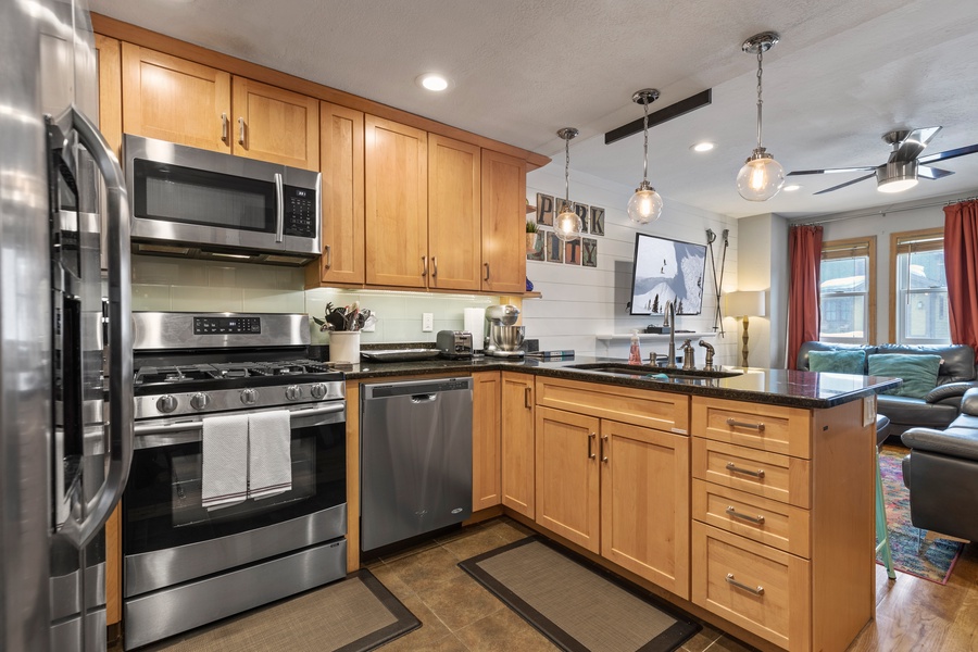 The well-equipped kitchen features stocked wood cabinets and a full suite of stainless steel appliances, making cooking delicious meals during your stay easy