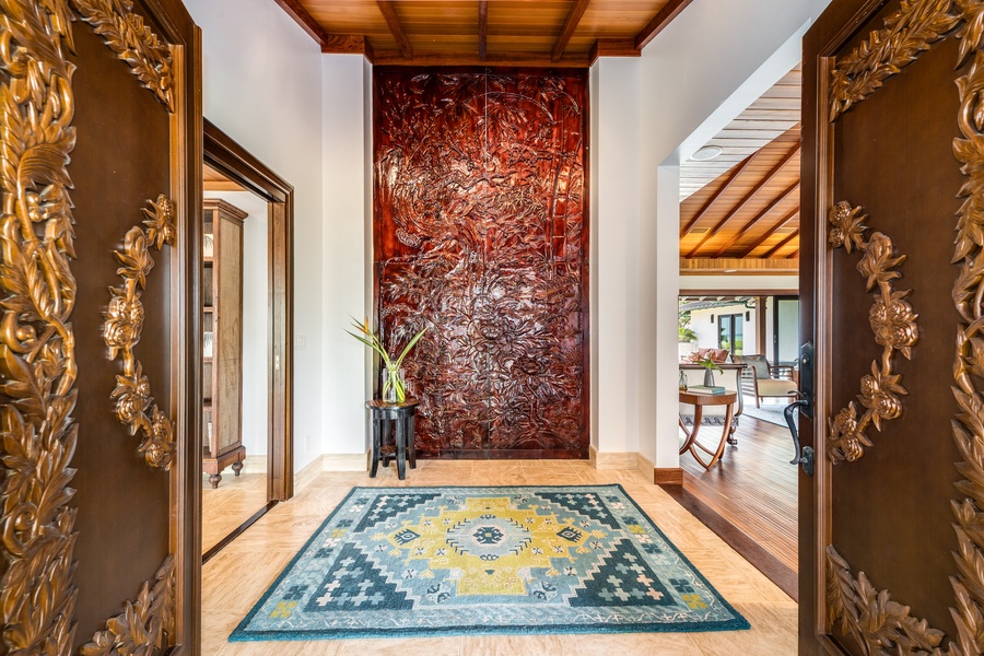 Ornate entryway sets the tone with custom-carved wood doors and natural stone feature wall.