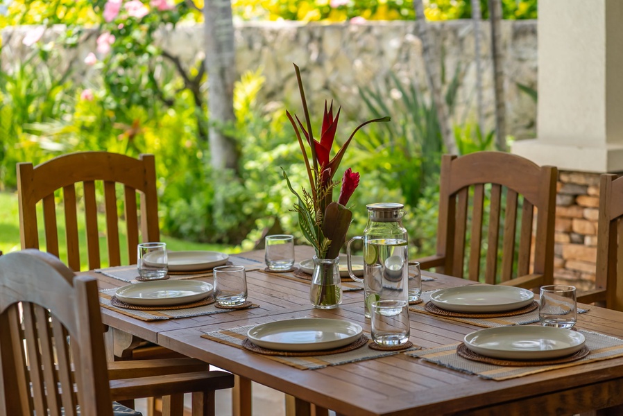 The covered outdoor dining area features tropical flora in a thoughtfully landscaped garden setting—a serene backdrop for memorable meals during your stay.