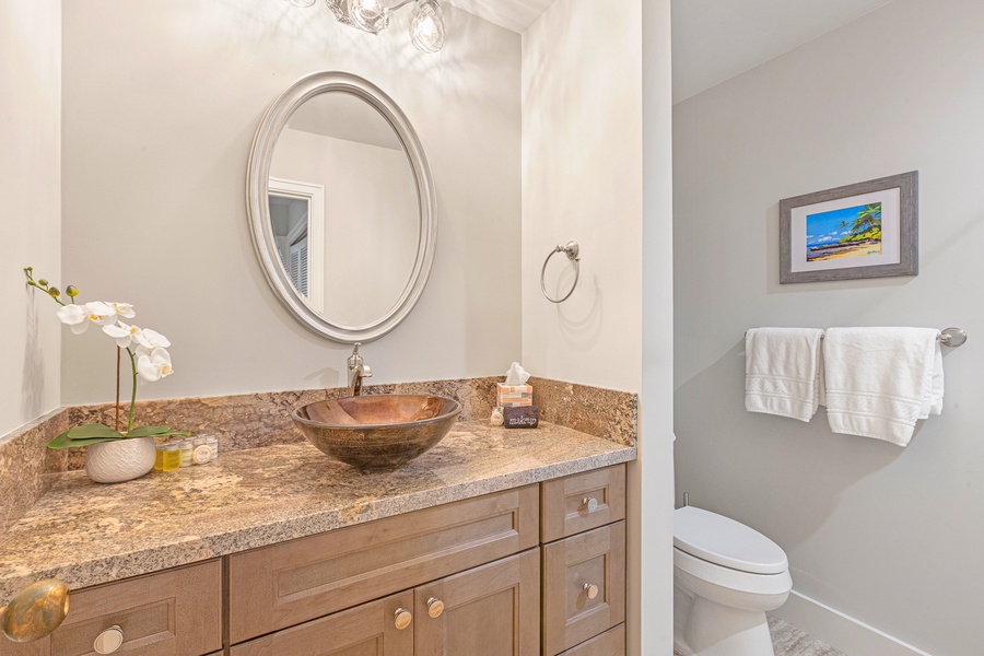 Freshen up in this elegant bathroom featuring a stylish vessel sink and a warm granite countertop for a touch of luxury.