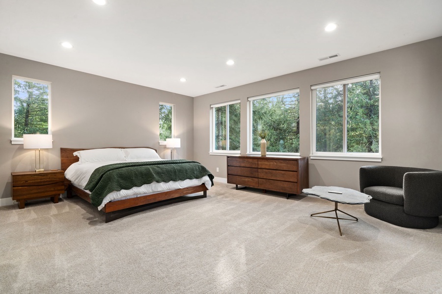 Drift off to sleep in this serene primary suite with its plush king bed, modern furnishings, and peaceful garden views.