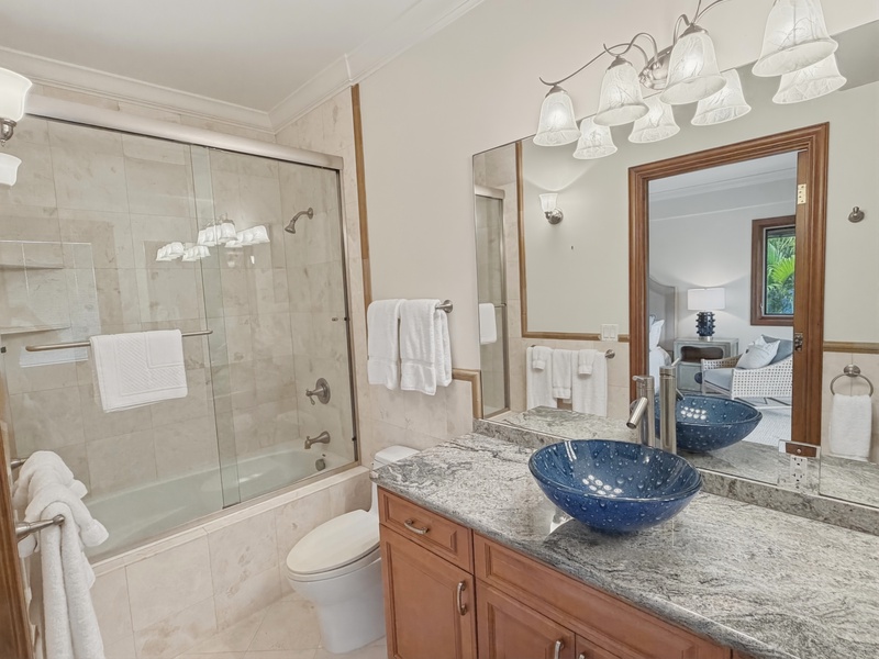 Your elegant bathroom features a deep soaking tub, rainfall shower, and stunning granite countertops with artistic blue glass basins.