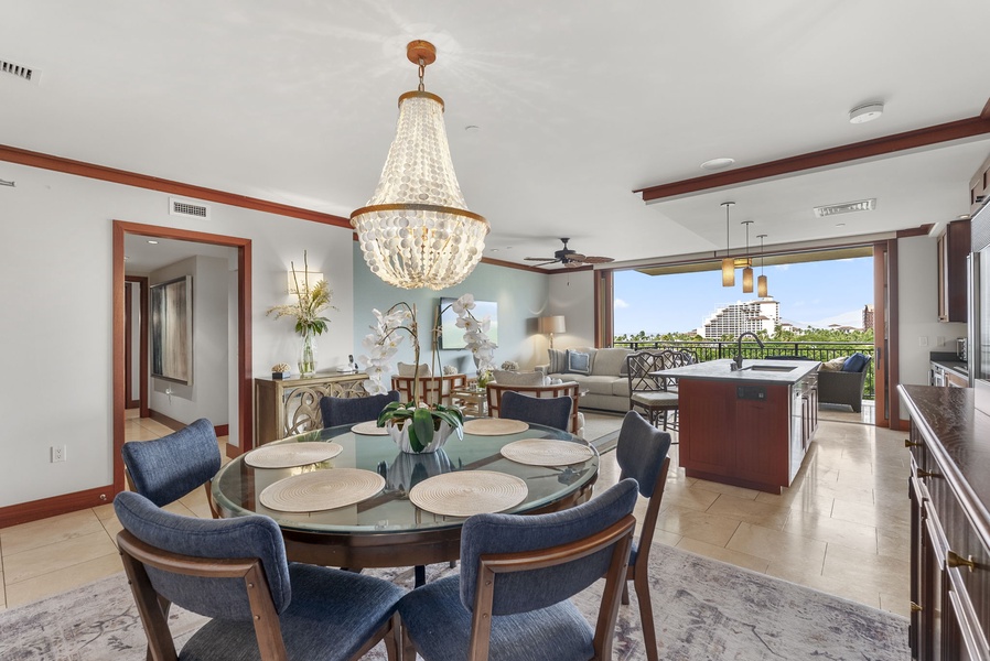 Gather around the elegant glass dining table under a stunning chandelier, while city views stretch beyond your private balcony.