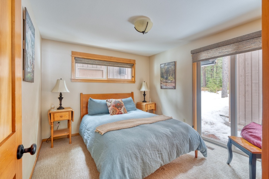 One of downstairs' guest bedroom offers a queen bed with central AC and a large glass windows