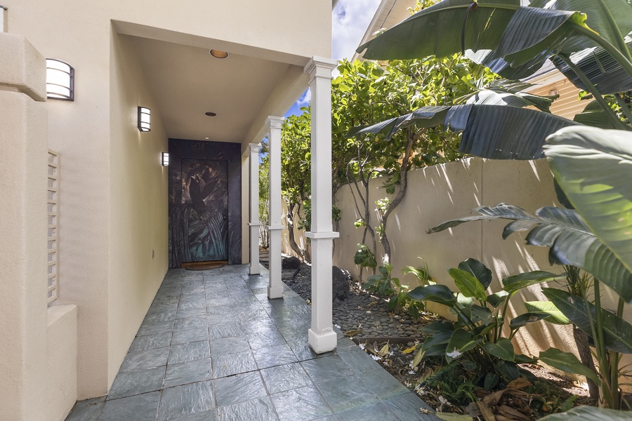 Covered walk way leads to engraved floral entry door.