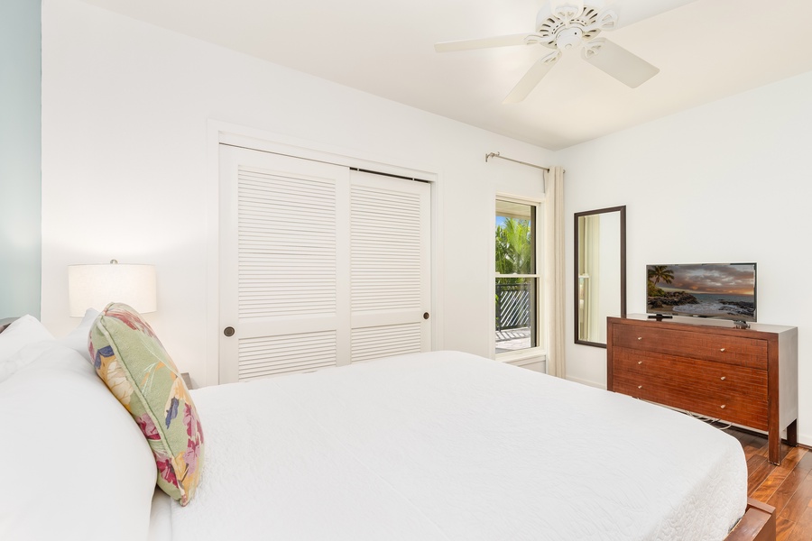 Features a plush bed, tropical views through sliding doors, and gentle ceiling fan breezes for perfect relaxation.
