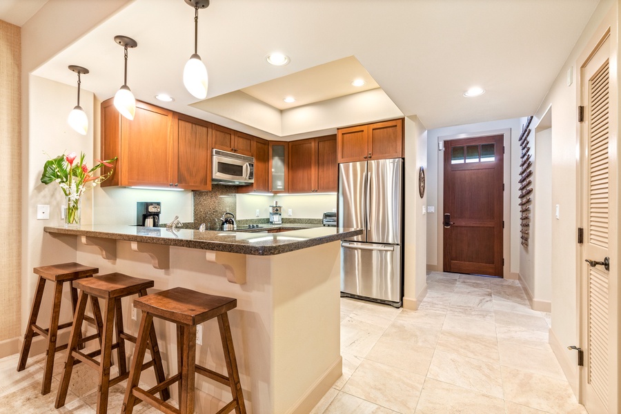 Wide view of open concept gourmet kitchen with granite countertops, stainless steel appliances and bar seating.