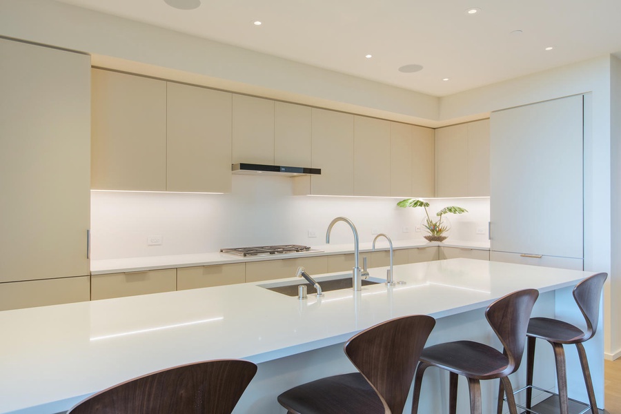 Your sleek gourmet kitchen features pristine white quartz counters, modern bar seating, and professional-grade appliances for memorable meals.