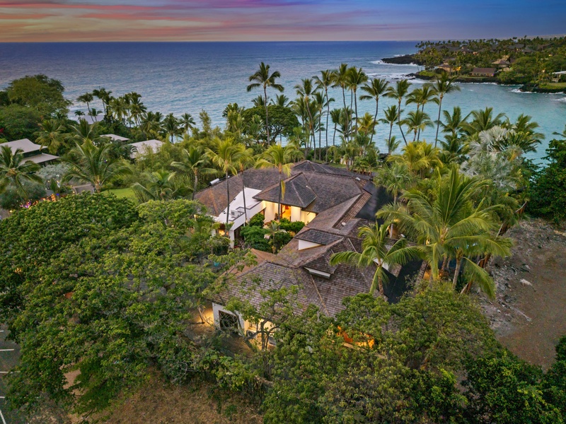 Stunning tropical paradise with dramatic sunset colors painting the sky above this secluded beachfront retreat surrounded by lush palms and pristine waters.