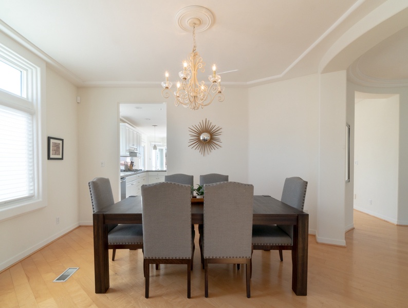 Sophisticated dining furniture and elegant chandelier gracefully adjoins the kitchen space